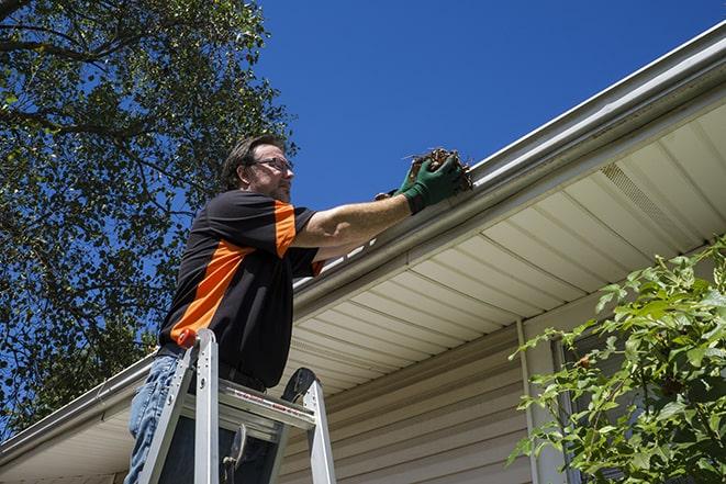 worker repairing a damaged gutter on a residential roof in Brier